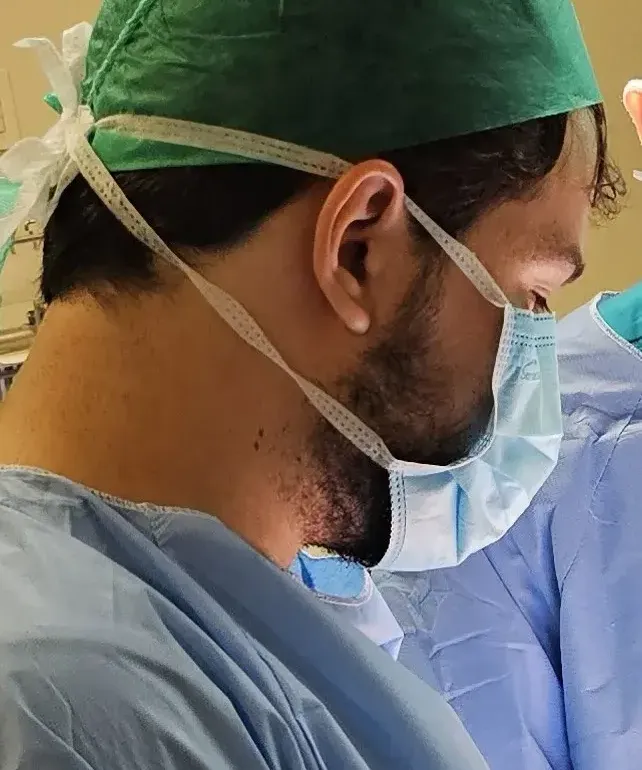 Dr. Pedro Siqueira paramentado, de gorro e máscara, durante uma cirurgia