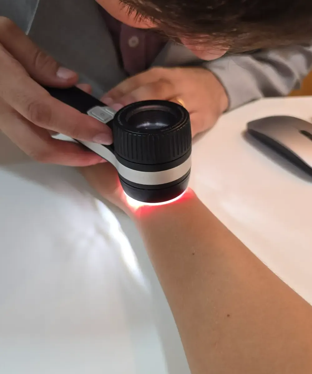 Dr. Pedro Siqueira examinando a pele do antebraço de um paciente com o dermatoscópio