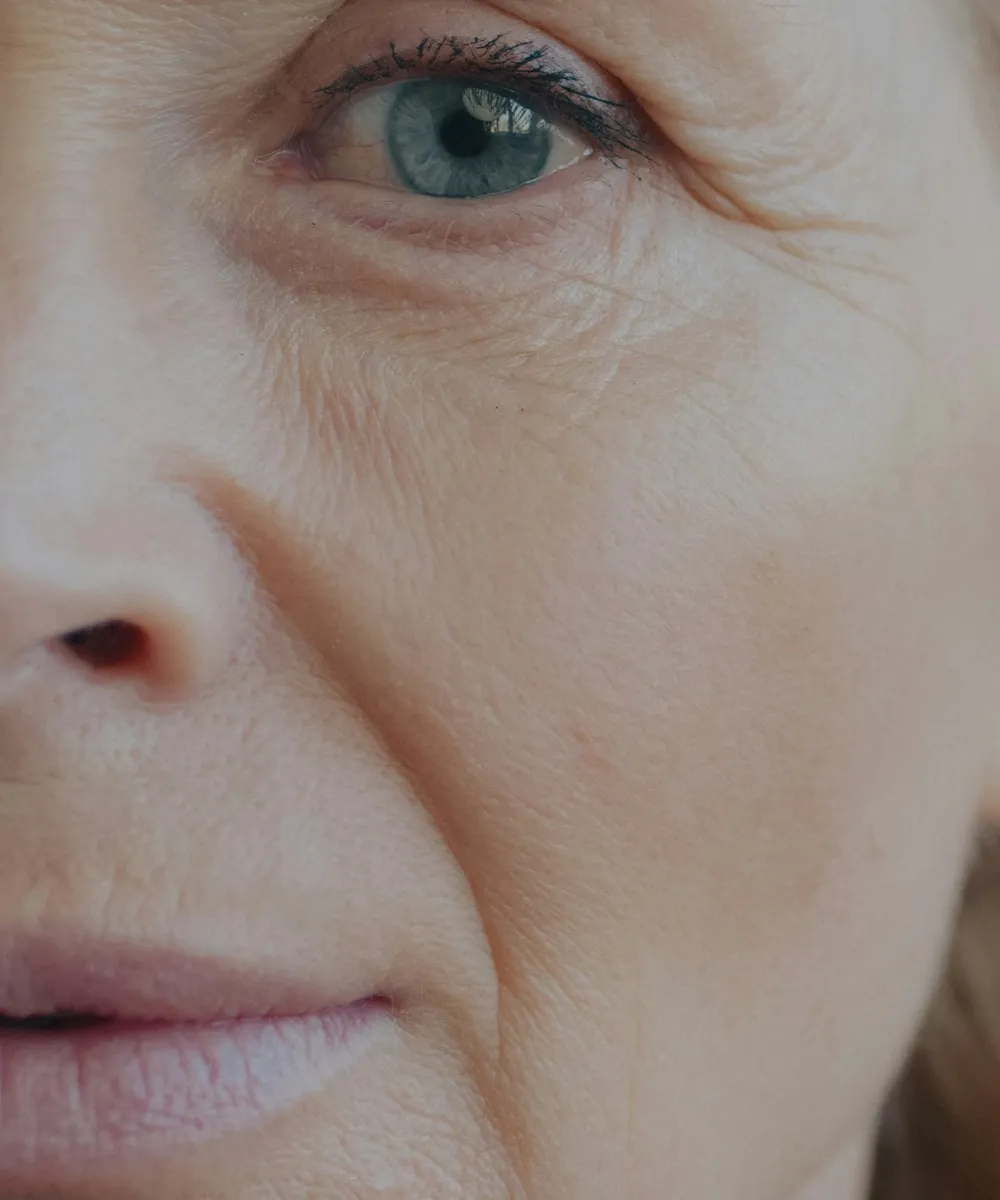 Detalhe da pele do rosto de mulher madura, com linhas finas ao redor dos olhos